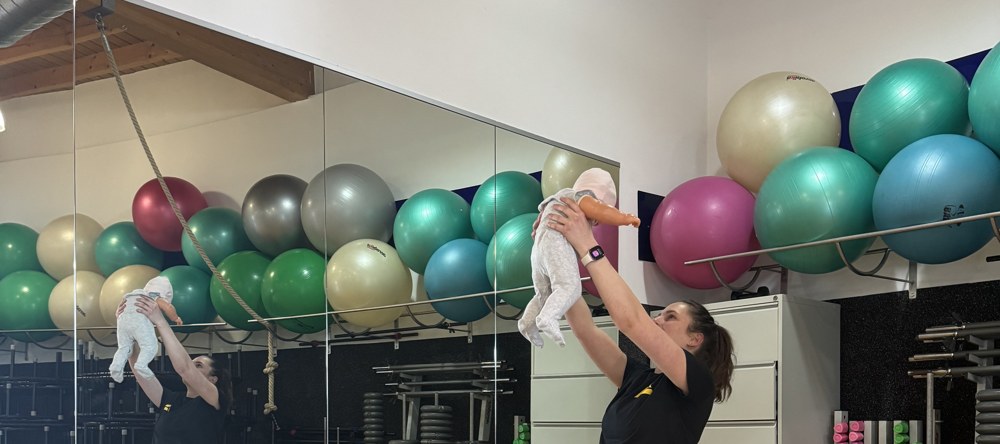 Mama mit Baby beim Fitness im Kursraum